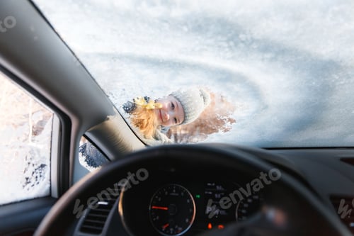 Preview: The kid helps and scraping snow and ice from car window. Girl is cleaning car from ice
