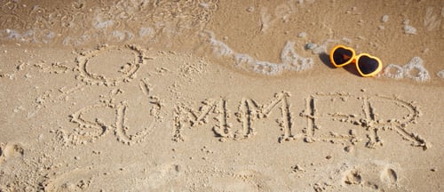 Preview: Word summer with shape of sun written on sand at beach and sunglasses. Travel and vacation time.