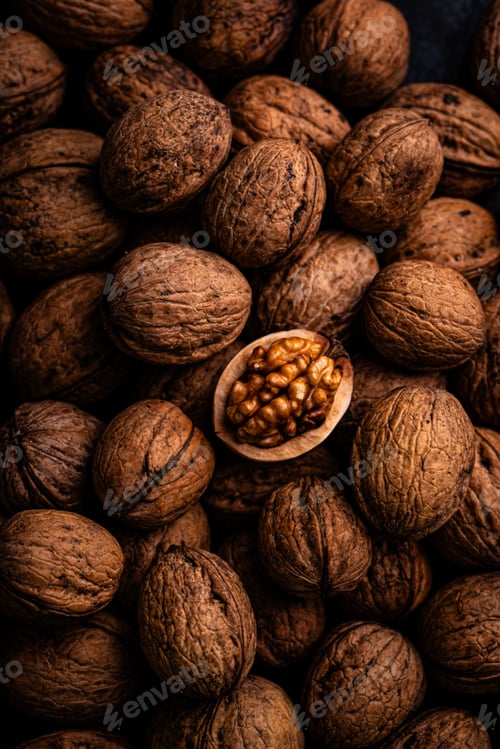 Preview: Cracked walnut in pile of whole walnuts