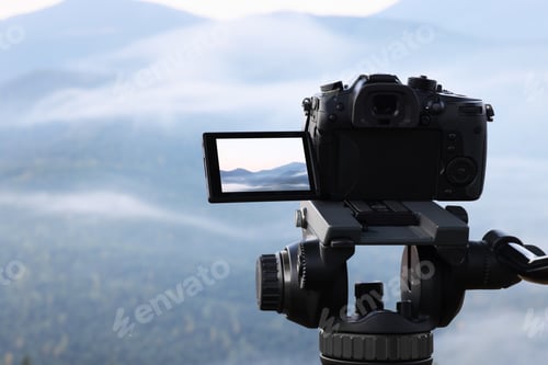 Preview: Taking video with modern camera on tripod in mountains