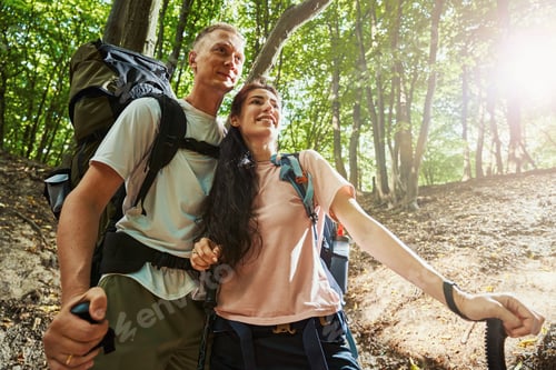 Preview: Joyful young people in love hiking in forest
