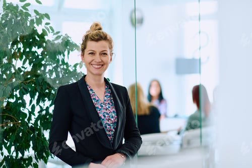 Preview: Portrait of a Blonde Businesswoman in a Modern Office with Her Workspace and Colleagues in the