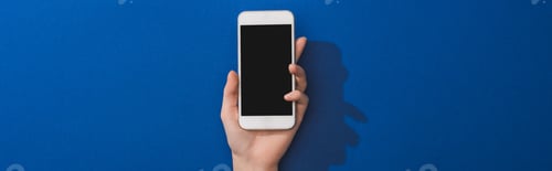 Vista previa: cropped view of woman holding smartphone on blue background, panoramic shot