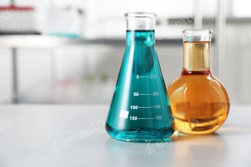 Preview: Flasks with color liquids on light table in laboratory. Space for text