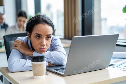 Preview: Exhausted Latino young businesswoman overworking in office workplace.