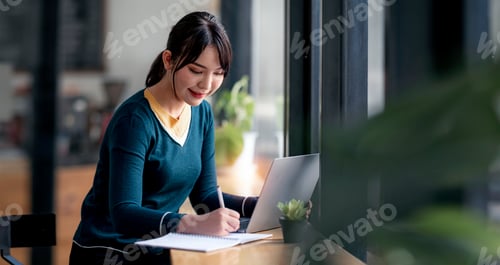 Preview: Young beautiful asian woman working on laptop computer at cafe.