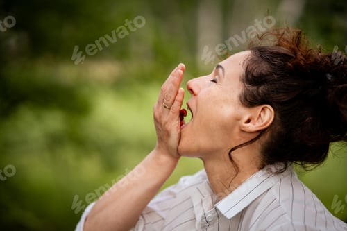 Preview: Woman in forest eating fresh wild berries on summer day natural food