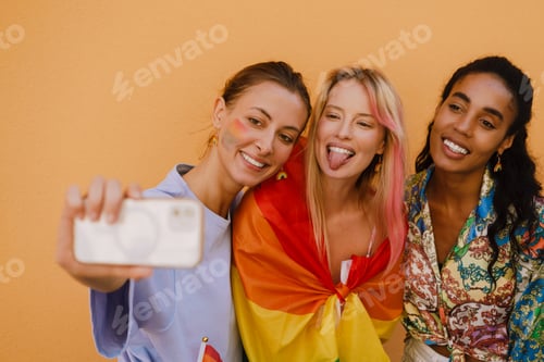 Preview: Young lesbian girls smiling and taking selfie photo over yellow wall