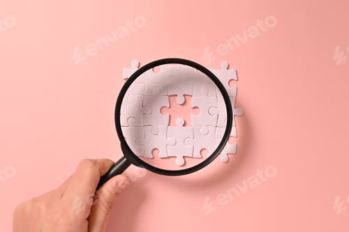 Preview: Hand holding magnifying glass with white square puzzle pieces grid of business background, Jigsaw on