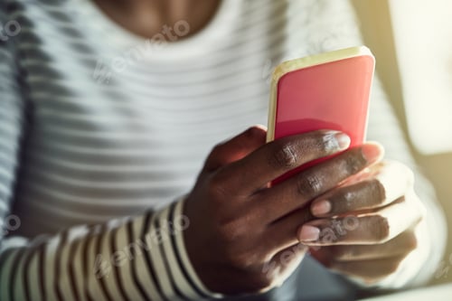 Preview: Young African woman reading text messages on her cellphone
