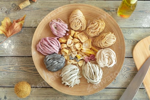 Preview: Various types of pasta arranged on a wooden plate with flour and ingredients around
