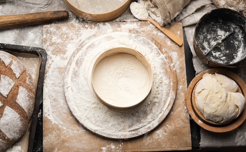 Preview: Kneaded dough of white wheat flour lies on a round wooden board