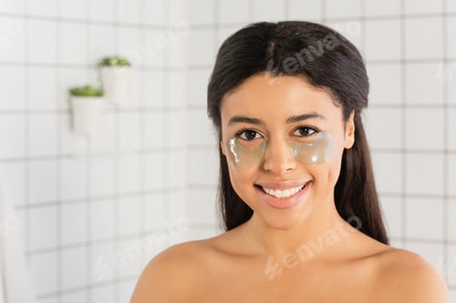 Preview: smiling young african american woman with eye patches looking at camera in bathroom
