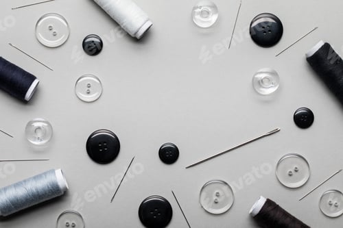 Preview: top view of black and transparent clothing buttons, needles and thread coils isolated on grey