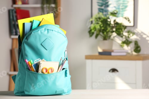 Preview: Turquoise backpack with different school stationery on white table indoors, space for text