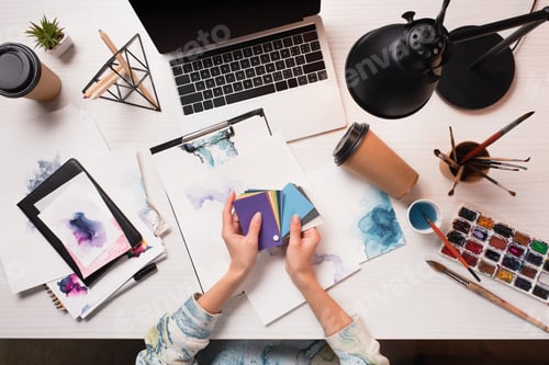 Preview: cropped designer working at office desk with laptop and art supplies