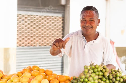 Preview: Smiling fruit vendor pointing at fresh oranges