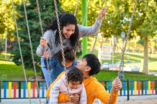 Preview: Latin family with two children playing together in a playground.