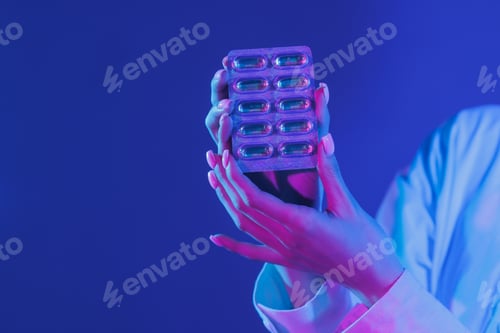 Preview: hand holding pills or drugs close up in ultraviolet color