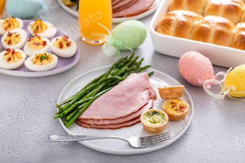 Preview: Easter brunch table with a potion of ham with asparagus on the plate