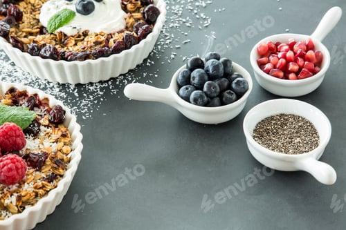 Preview: High angle of two bowls of oatmeal with raisins and fruit next t