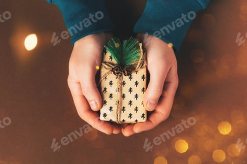 Preview: Male hands holding gift box on brown background