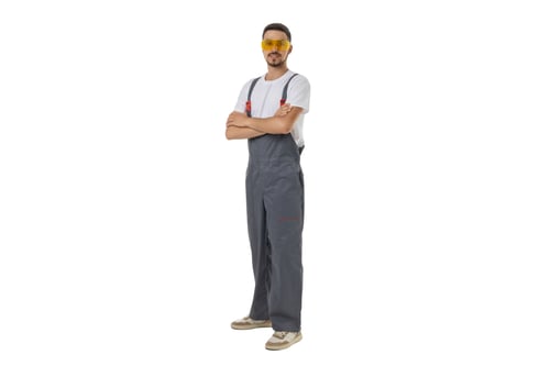 Preview: Worker in Overalls With Arms Crossed Stands Confidently