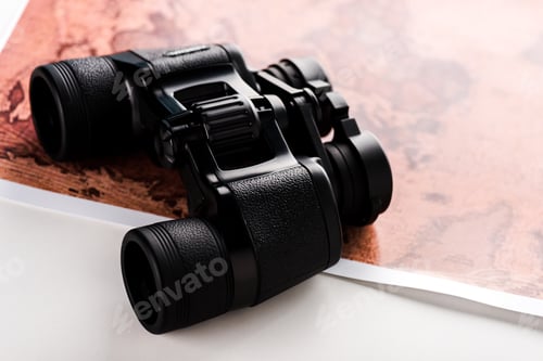 Preview: selective focus of black binoculars on map on white