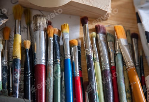 Preview: Paintbrushes used with stains on wooden table. Blur over view background.