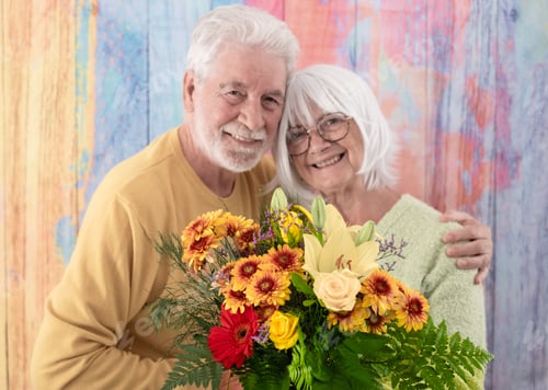 Preview: Valentine's day. Smiling senior couple exchanging a flower bouquet.