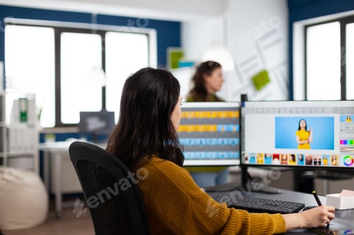 Preview: Photographer woman sitting at desk listening music using PC in photo studio