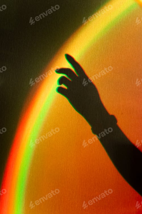 Preview: Shadow of womans hand. Rainbow reflection of sunbeam on wall. Hand touches rainbow.