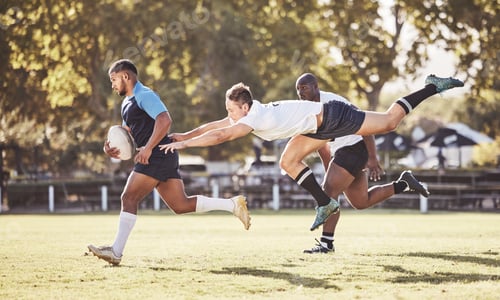 Preview: Caucasian rugby player attempting to tackle an opponent during a rugby match outside on the field.