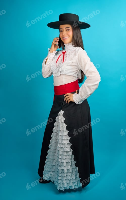 Preview: Smiling woman wearing traditional huasa dress talking on cellphone on turquoise background