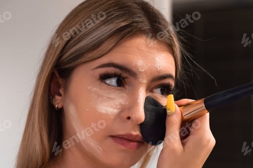 Preview: Young woman, teenage girl is applying make up with a brush in a bathroom, getting ready to go out