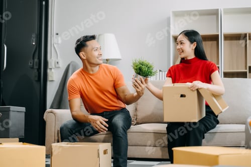 Preview: Happy asian young attractive couple man and woman with big boxes moving into a new house