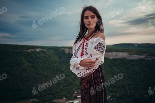 Preview: Atractive woman in traditional romanian costume on mountain green blurred background