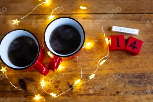 Preview: Two cups of coffee in red cups on a background of garlands. Postcard with date and month.