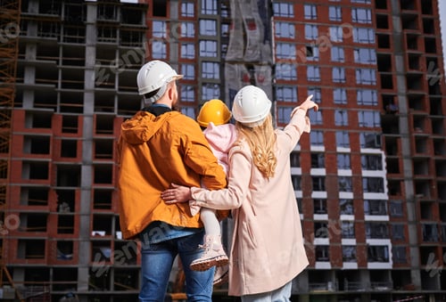 Preview: Family with child looking at apartment building under construction.