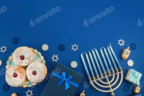 Preview: Jewish holiday Hanukkah concept. Frame of traditional jelly donuts and menorah on dark blue