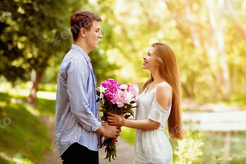 Preview: Romantic millennial guy presenting bouquet of beautiful flowers to his girlfriend in park