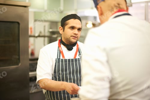 Preview: Chef lecturer explaining recipe to teenage catering student in college kitchen
