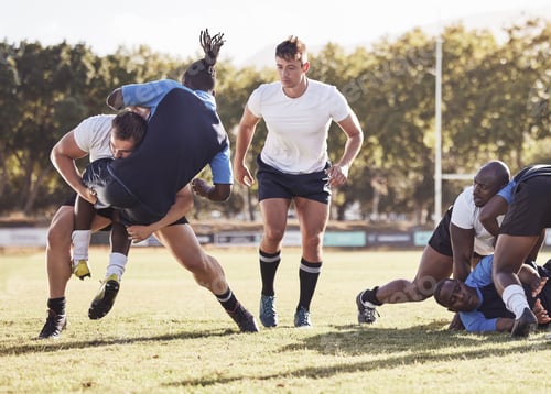 Preview: Caucasian rugby player attempting to tackle an opponent during a rugby match outside on the field.