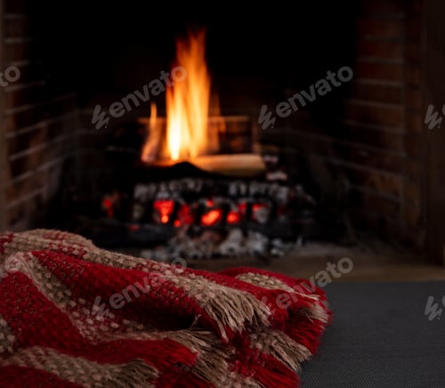 Preview: Blanket on fireplace burning wood logs background. Relaxation and Christmas holiday, cozy warm home