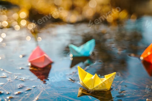 Preview: Multicolored paper boats. Colorful pink yellow blue orange ships in big spring snow puddle on
