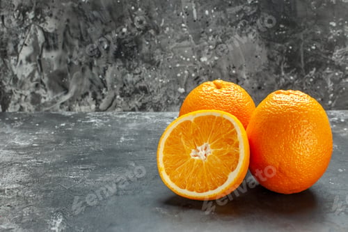 Preview: Side view of vitamin source cut and whole fresh oranges on gray background
