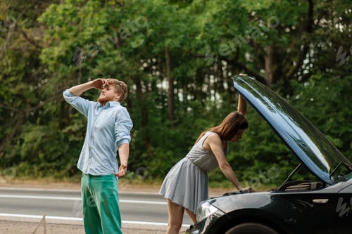 Preview: Tired couple at the opened hood, car breakdown