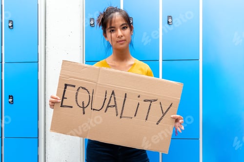 Preview: Teen asian girl looking at camera carrying an vindictive equality sign banner in high school.