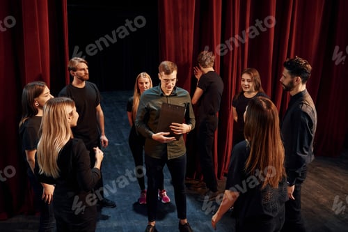Preview: Practice in progress. Group of actors in dark colored clothes on rehearsal in the theater