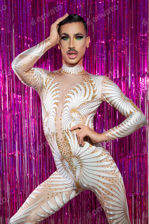 Preview: young drag queen with short hair and mustache posing with fuchsia color background